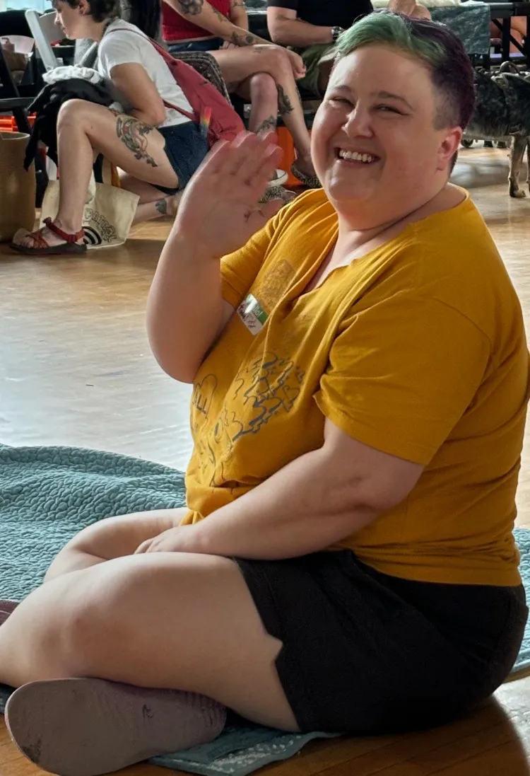 Trubbs inside at event venue, laughing on floor, with close cropped hair